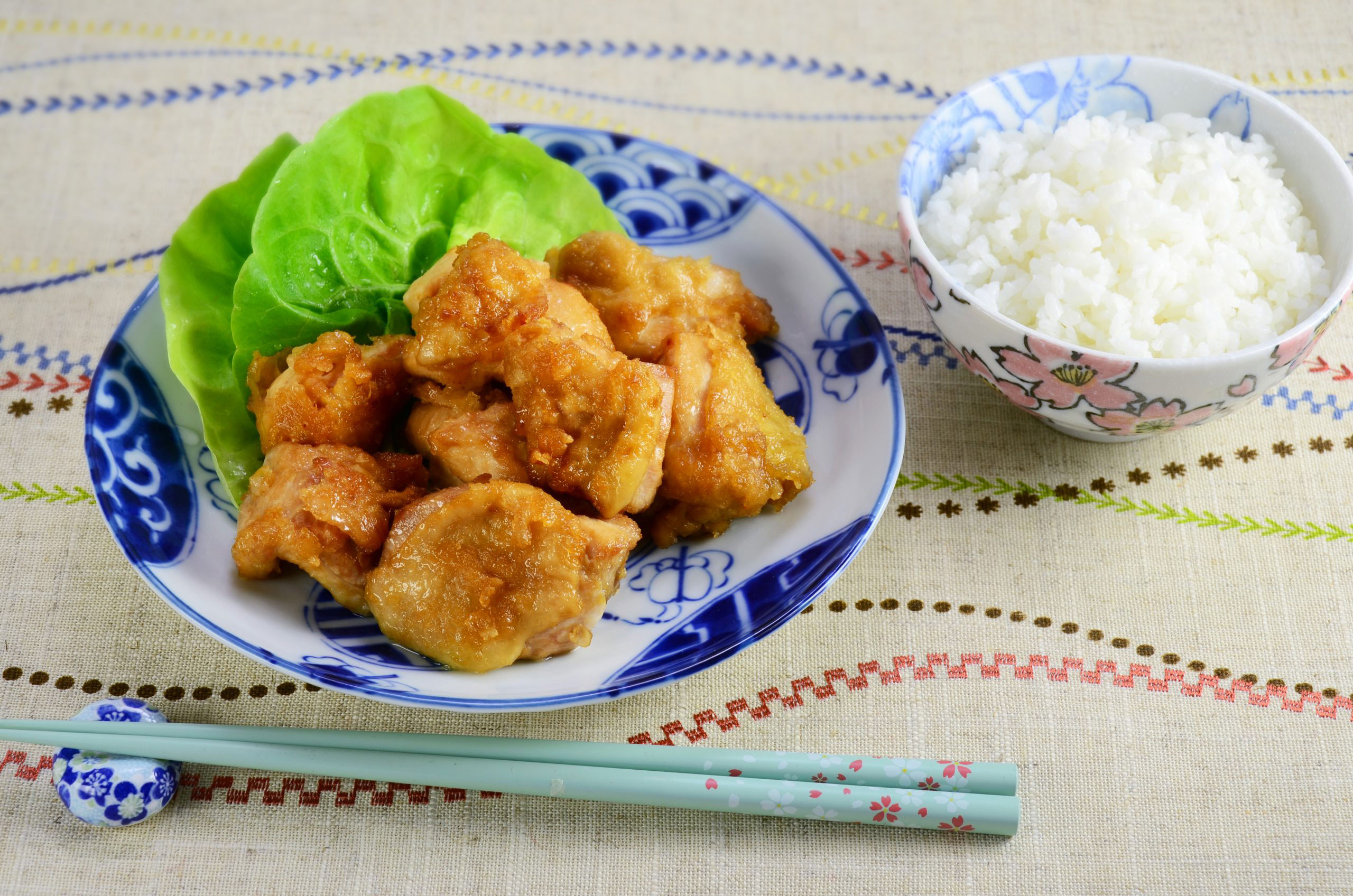 Plate with golden and crispy fried chicken karaage served with a bowl of white rice
