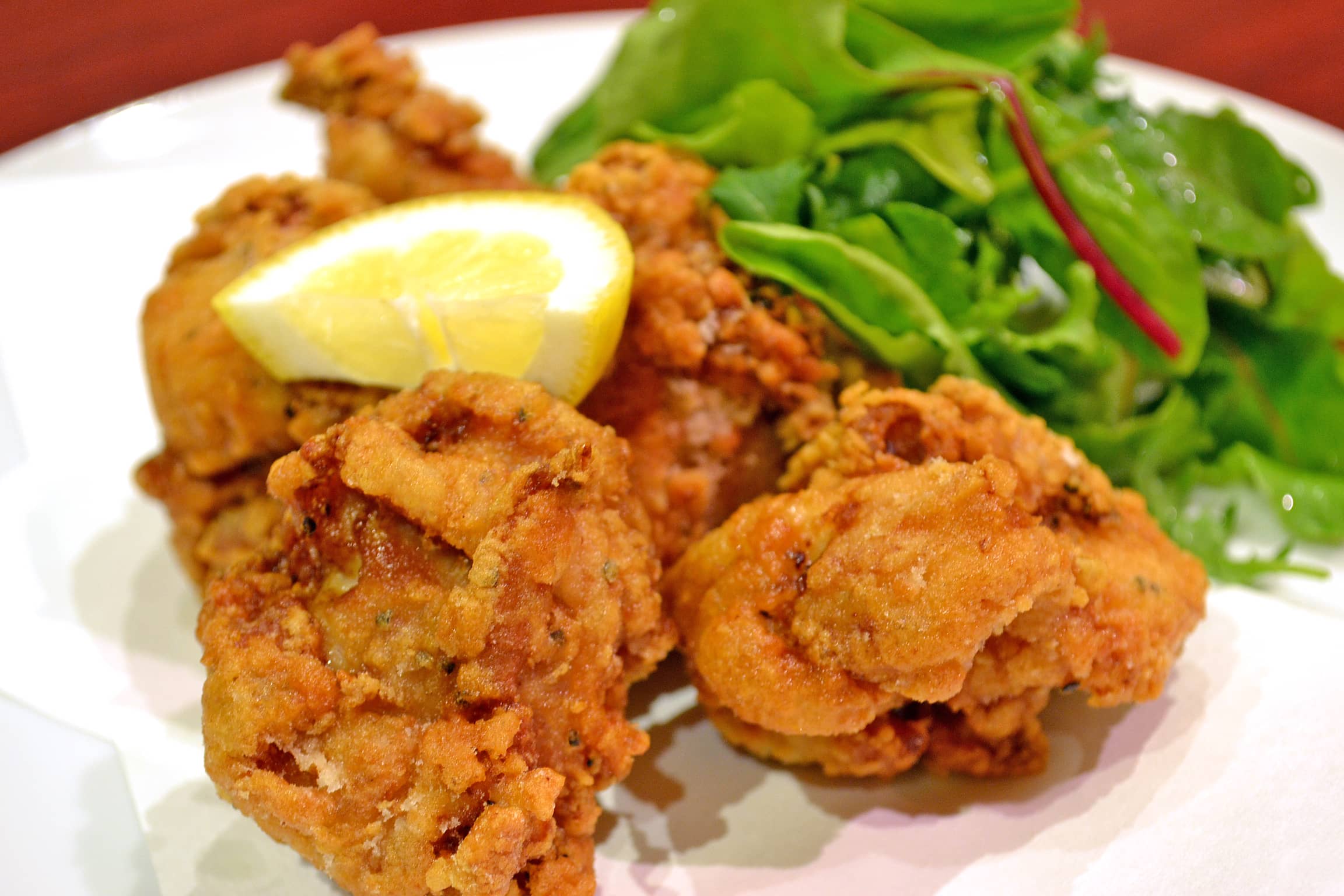 Golden fried chicken karaage with a side of a leafy salad and a slice of lemon