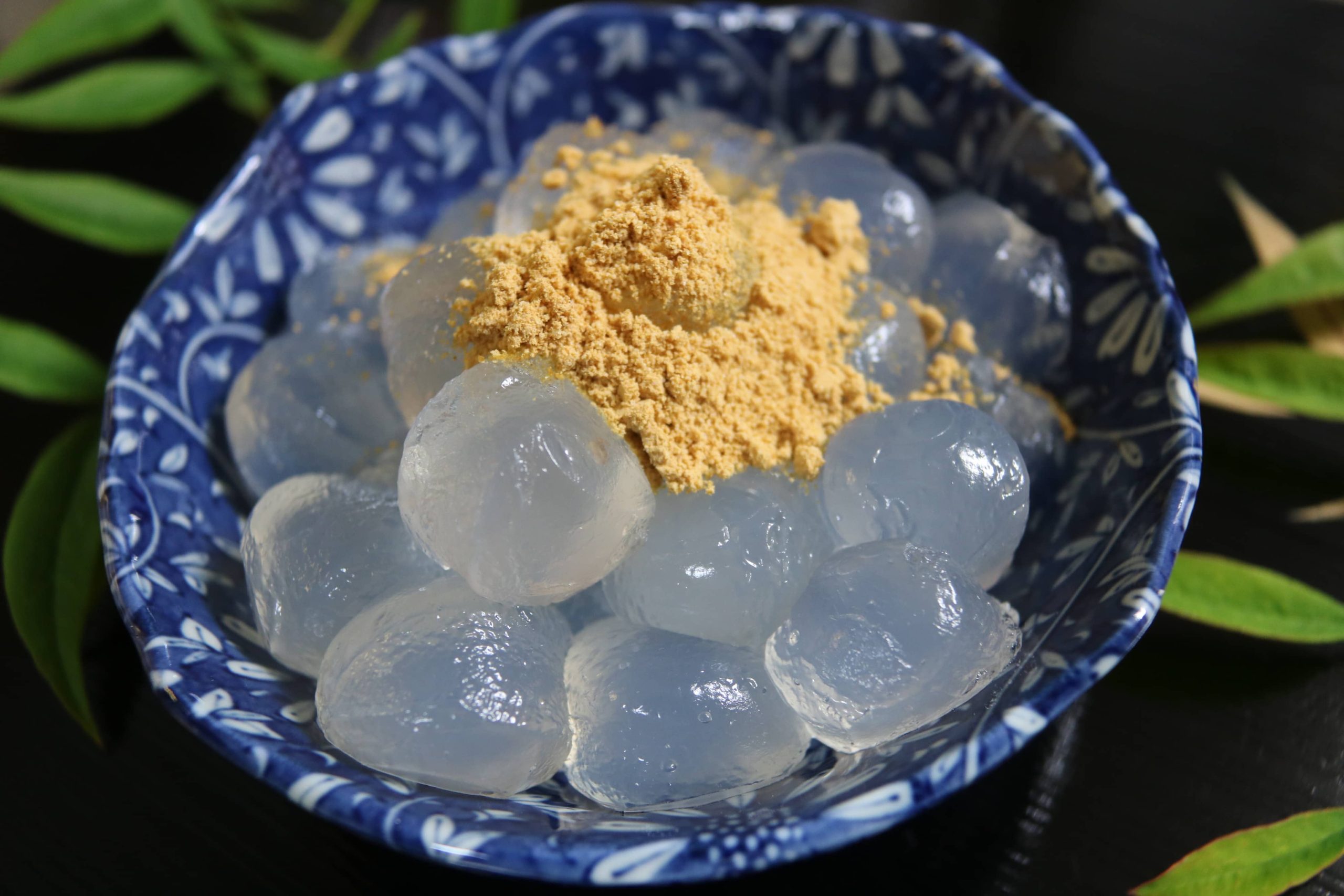 Bowl filled with glossy warabi mochi spheres topped with golden sweet soy bean powder
