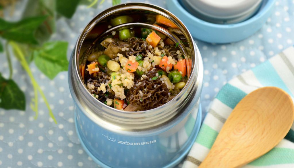 Lunch setting with a light blue food jar filled with a vegetable salad with couscous