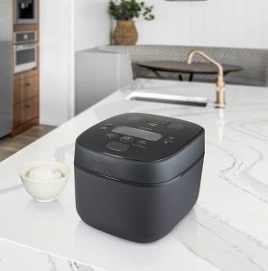 Bright kitchen with white marble countertops with a kitchen island and a modern rice cooker in black in the foreground