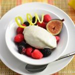 White bowl with mixed berries and a portion of gelato over it.