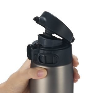 Hand holding a stainless steel mug while the lid is mid opening 