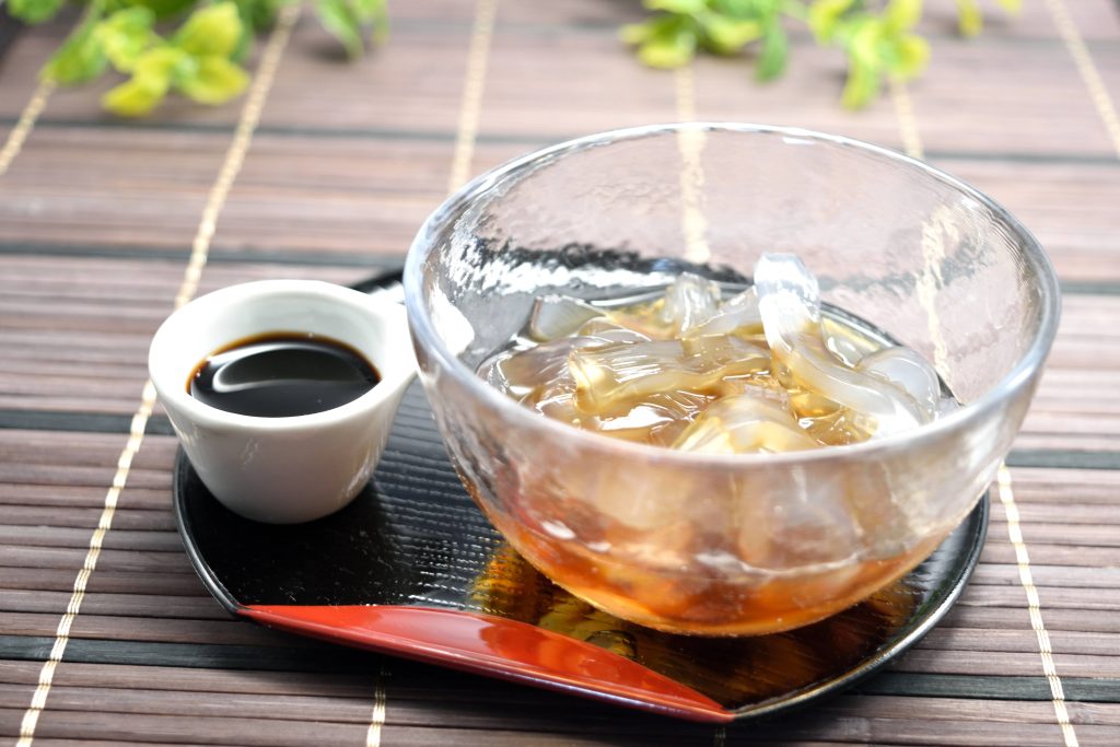 Glass bowl with translucent strips over served with a small bowl of sauce over a traditional Japanese lacquerware plate 