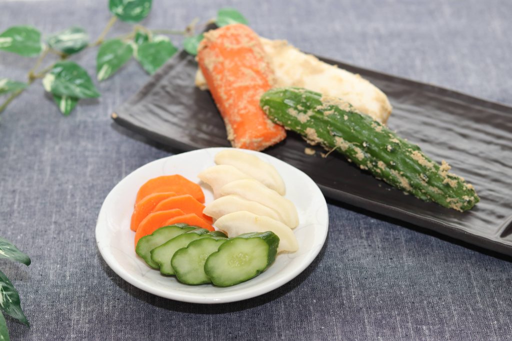 A white round plate with sliced pickles and a long black plate with whole veggie pickles.