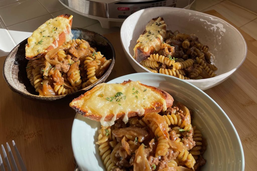 French Onion Pasta served in small bowls topped with cheese toasted roll