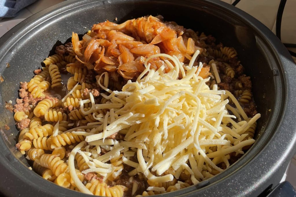 Cooked pasta and ground beef, topped with browned onions and shredded cheese