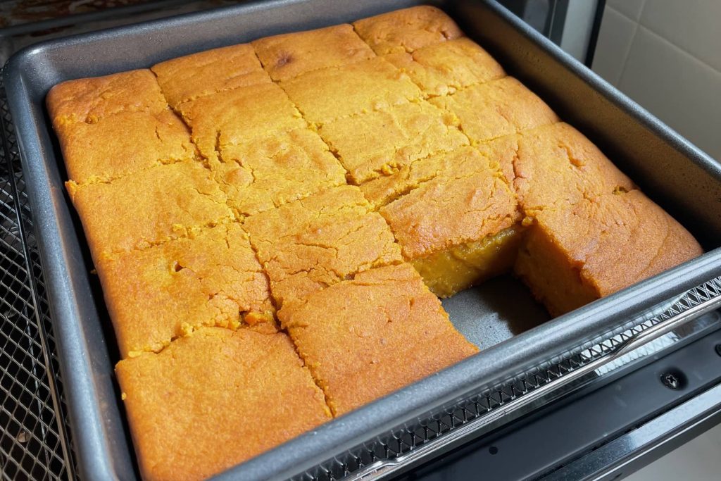 Pumpkin mochi cake baked in a pan, cut into squares and coming out of toaster oven
