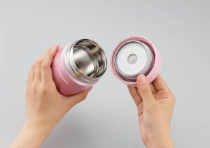 Hands holding a pink food jar: Left hand holds the main jar and the right hand holds the lid