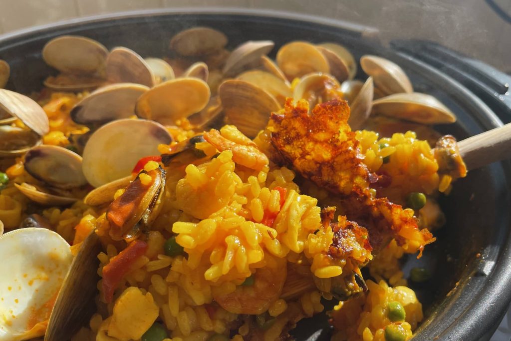 Close-up of paella dish showing underside of seared crispy rice