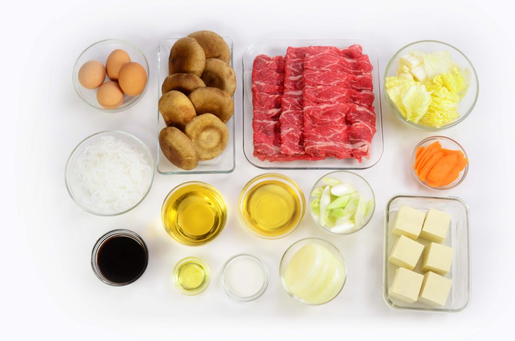 Spread of various ingredients like meat, shiitake mushrooms, eggs, cabbage, tofu and various sauces