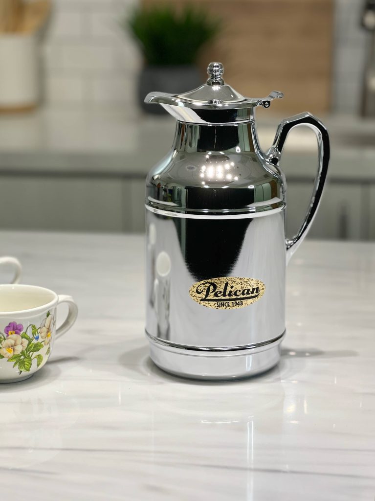 Chrome carafe with a vintage cup on a marble surface in a kitchen