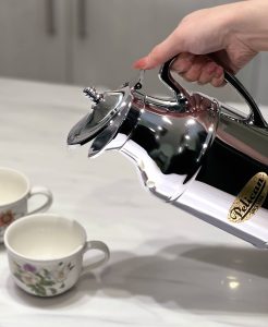 Someone is pouring from the chrome carafe into small vintage cups