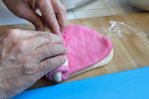hand rolling pink and white dough together