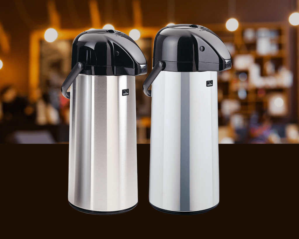 Two chrome beverage dispensers side by side with a busy coffee shop on the background