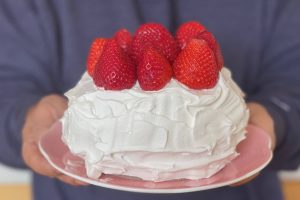 Strawberry short cake on plate, being held and presented