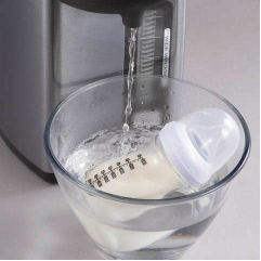 Hot water being poured from the water boiler into baby formula in a clear bowl.