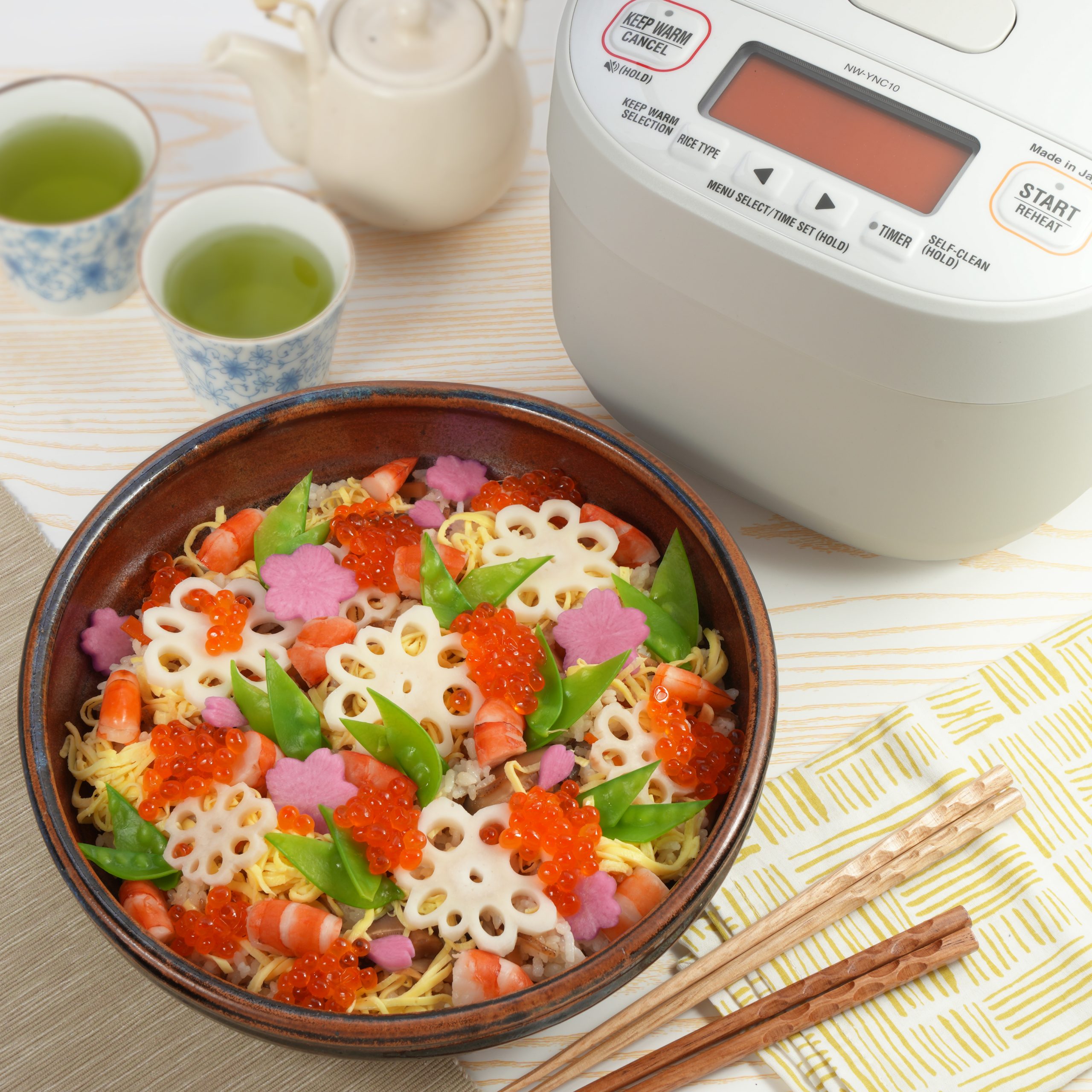 Chirashi sushi next to a white rice cooker