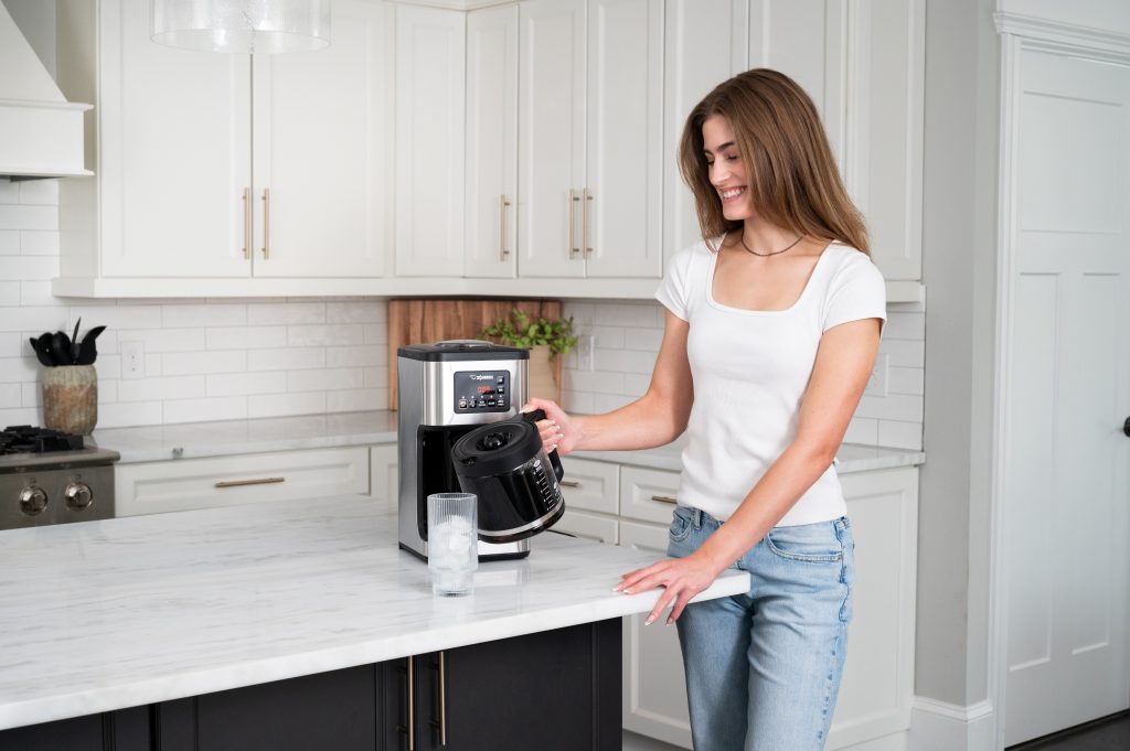 A female pouring coffee with coffee carafe in the kitchen