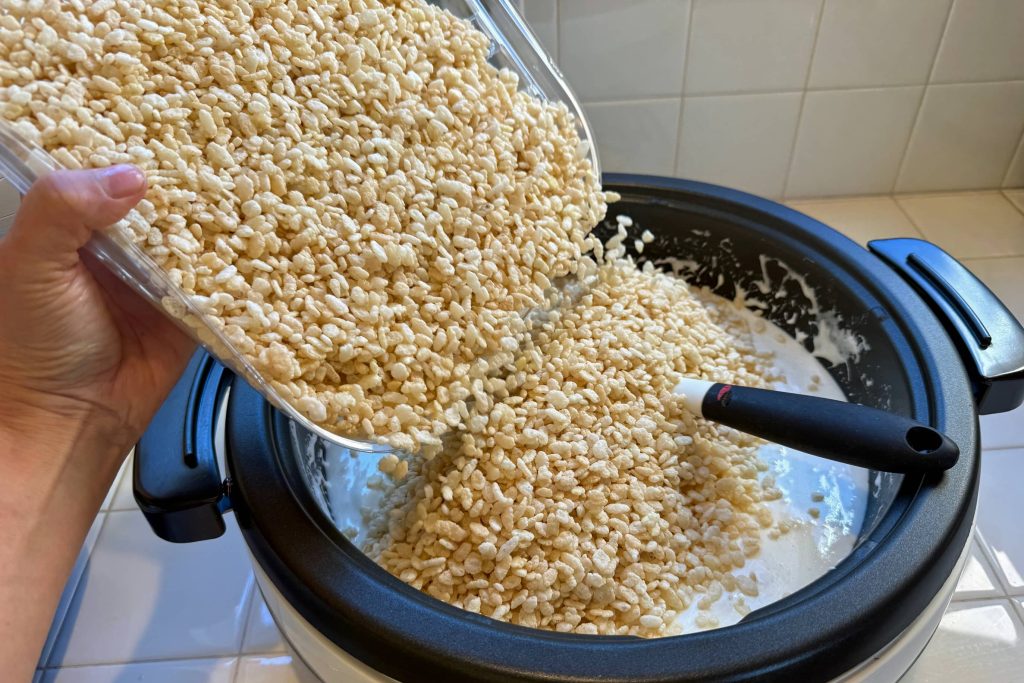 pouring rice krispies cereal into pan