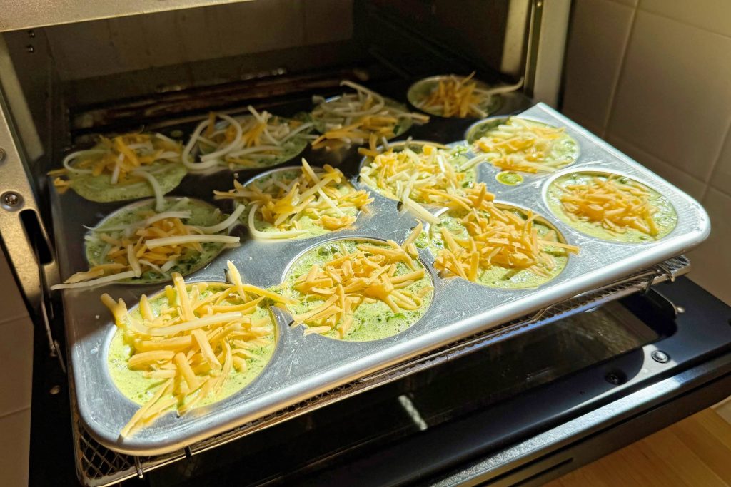 green eggs in muffin pan loaded into toaster oven