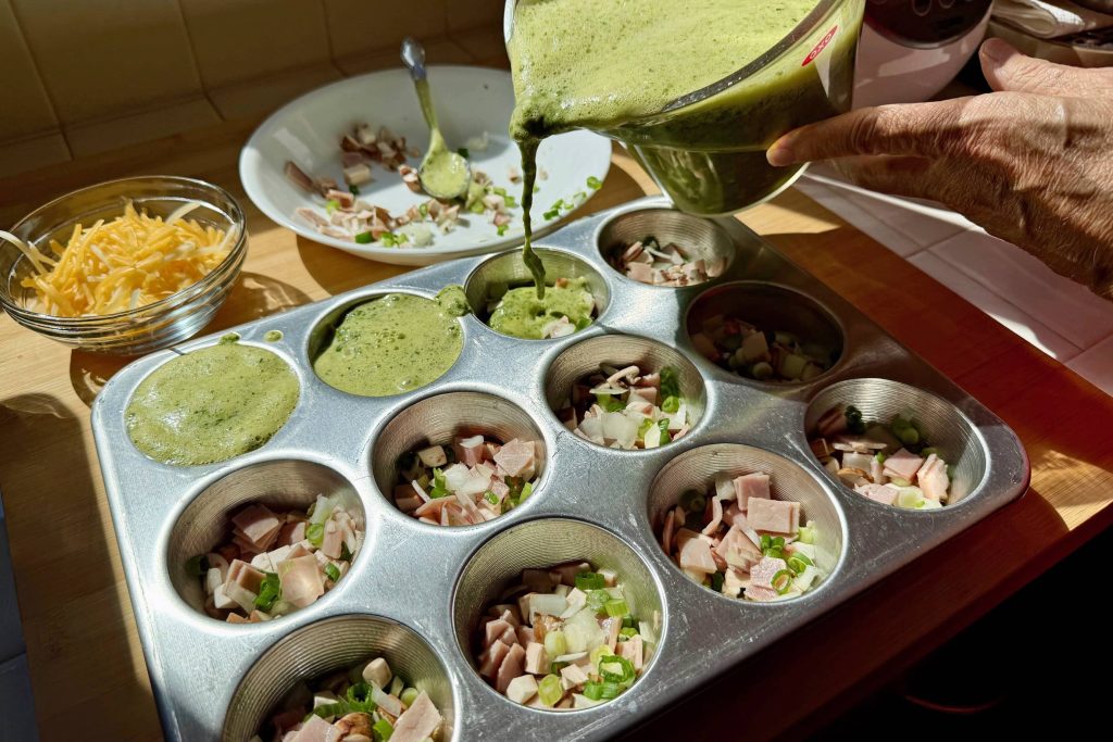 green eggs mixture being poured into muffin pan