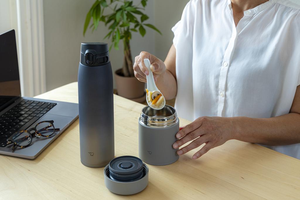Grey food jar and bottle on the desk next to laptop