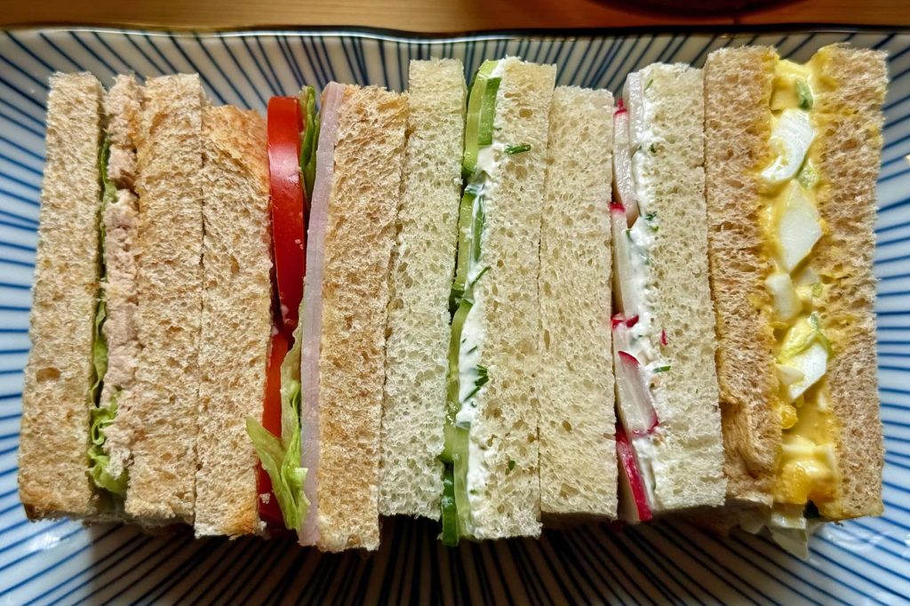 sandwiches shown from sides--tuna, ham, cucumber, radish, egg salad