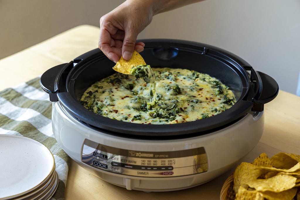 Dipping a chip in the spinach dip in the electric skillet