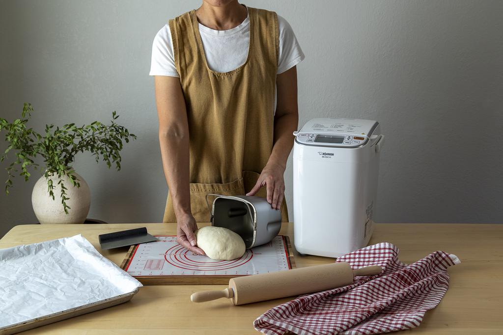taking out the dough from the baking pan next to the breadmaker