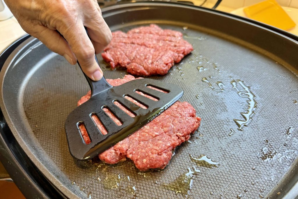 preparing smash burger patty on the griddle