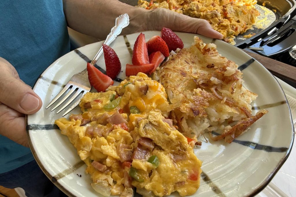 Plated Denver scrambled eggs with hash browns and fresh cut strawberries