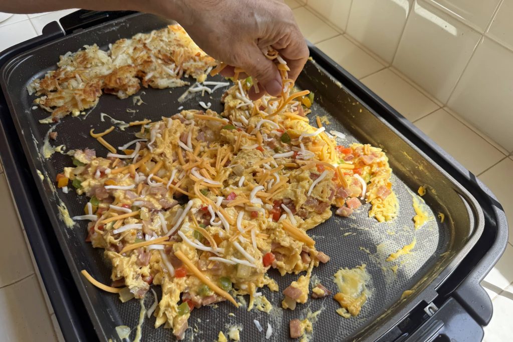 Sprinkling shredded cheese on to Denver scramble eggs