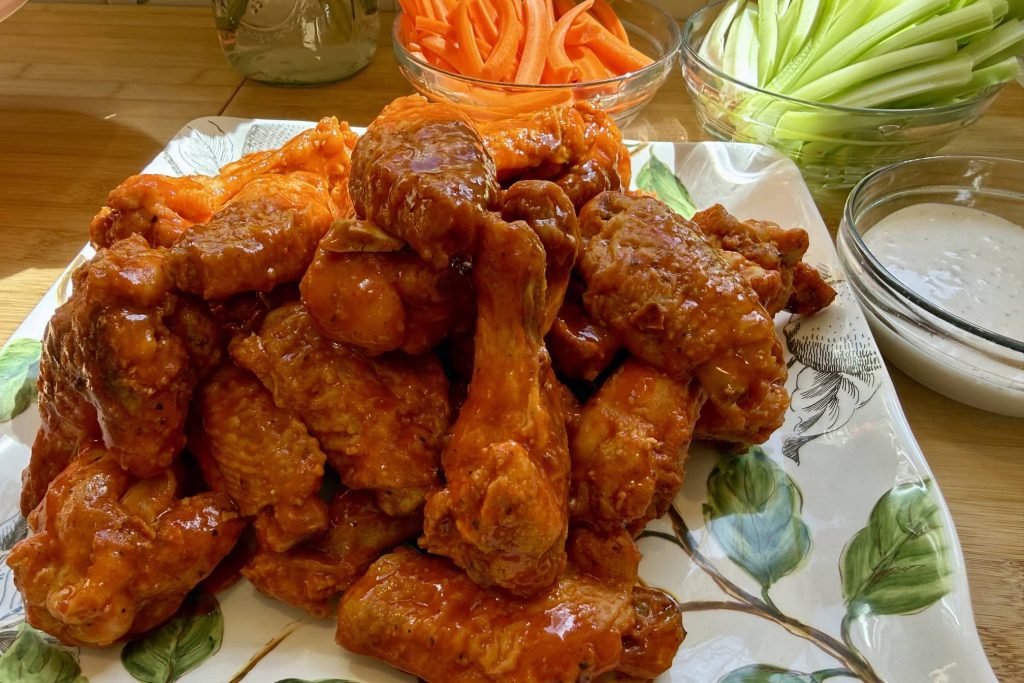 Buffalo Chicken Wings plated, with sides of carrot and celery sticks and ranch dressing