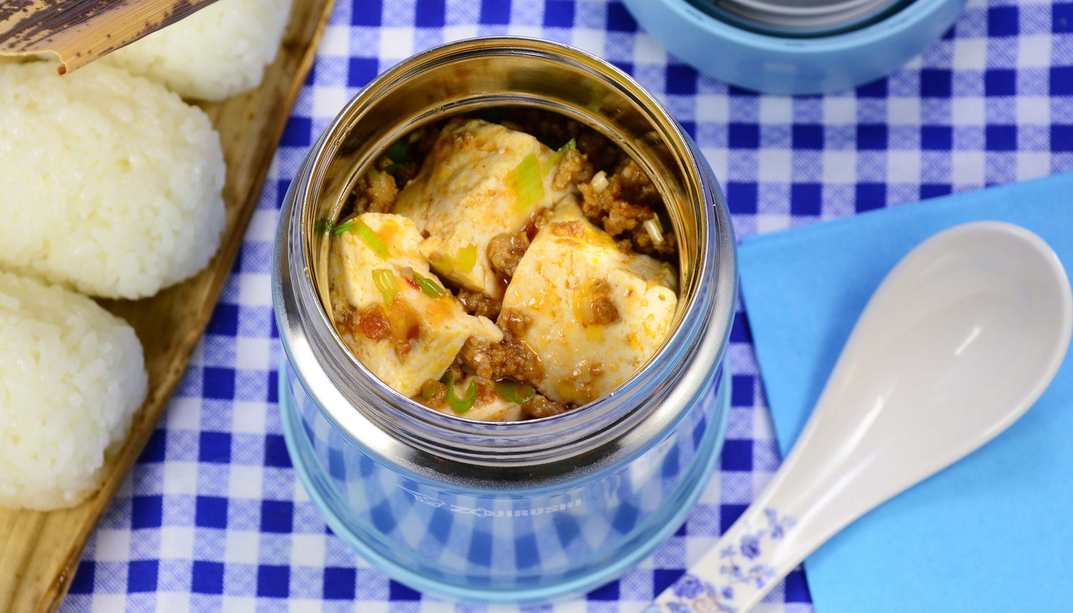 Blue vacuum insulated food jar filled with spicy mapo tofu served with rice balls